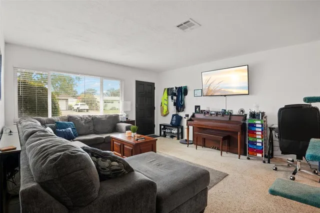 a living room with furniture a floor to ceiling window and a flat screen tv