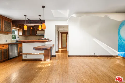 a kitchen with kitchen island a stove a sink and a wooden floor