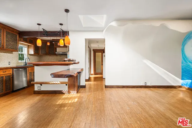 a kitchen with kitchen island a stove a sink and a wooden floor
