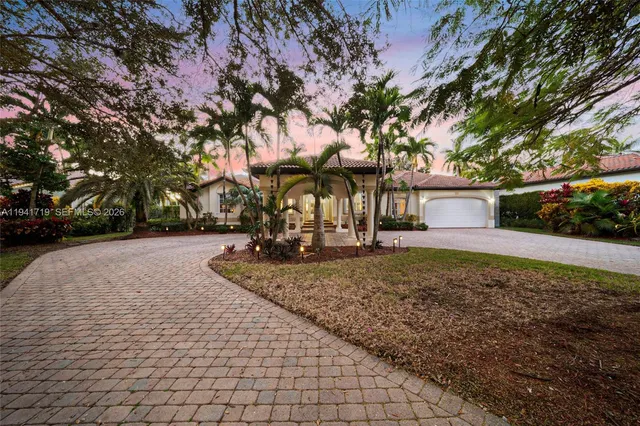 a front view of a house with a garden and trees