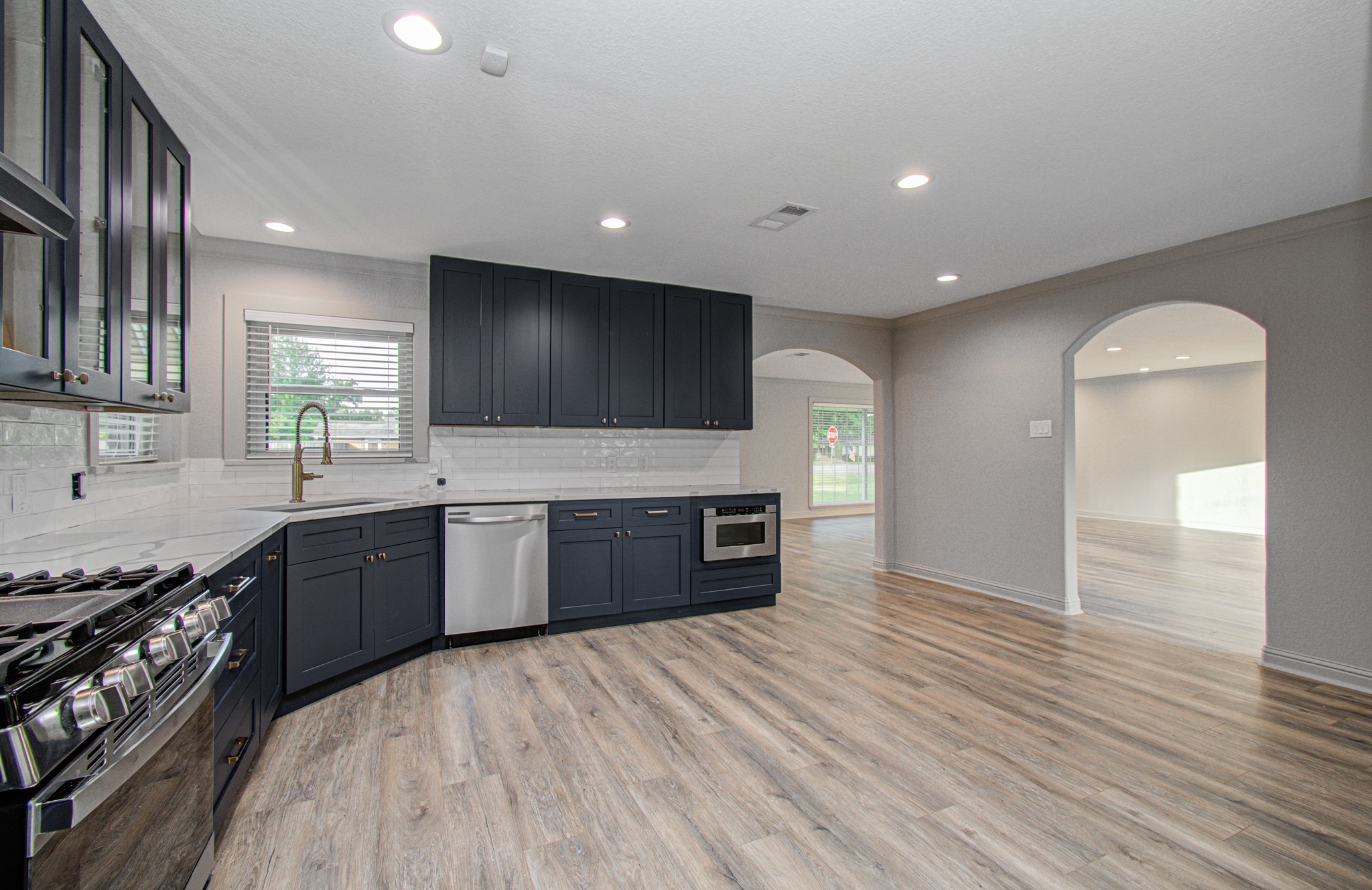 1801 Benbow Way Houston, TX 77080 - Photo 13 of 32 This modern kitchen features sleek dark cabinets, stainless steel appliances, and a spacious open layout with ample natural light and elegant wood flooring.