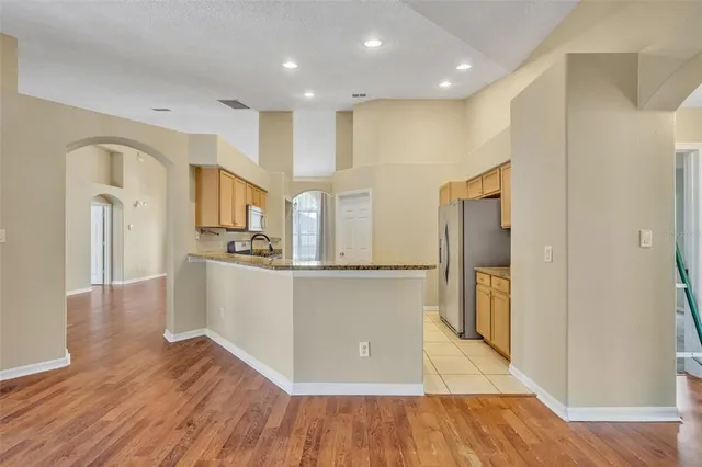 a large kitchen with stainless steel appliances granite countertop a large counter top and a wooden floors