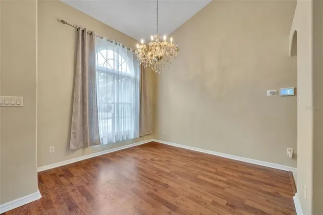 a view of a chandelier in big room with wooden floor