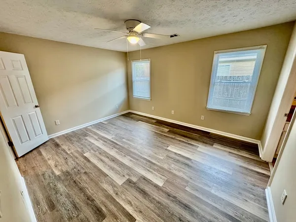 a view of an empty room with wooden floor and a window