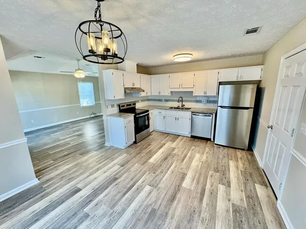 a kitchen with granite countertop stainless steel appliances and wooden floor