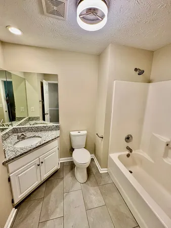 a bathroom with a granite countertop sink toilet and mirror