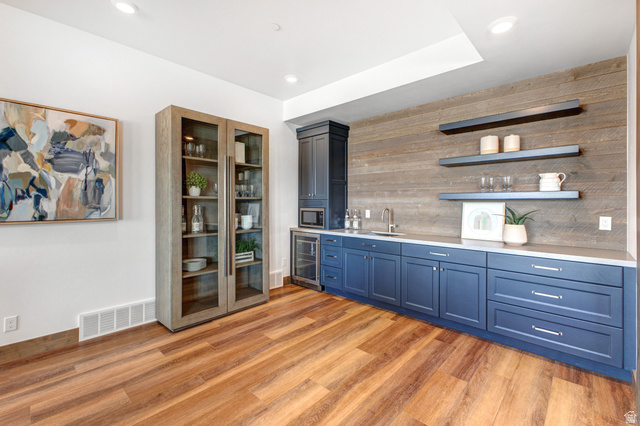 1282 Chimney Rock Road, Unit 344 Heber City, UT 84032 - Photo 36 of 55 Entertainment space featuring wood-finish flooring, a full wet bar with blue cabinetry, a beverage refrigerator, and a built-in microwave