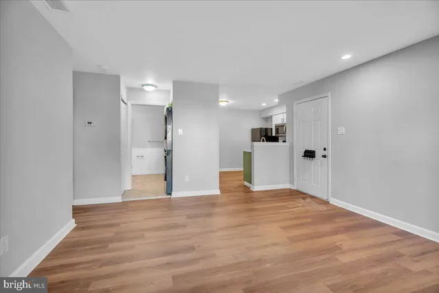 a view of an empty room with wooden floor and a window