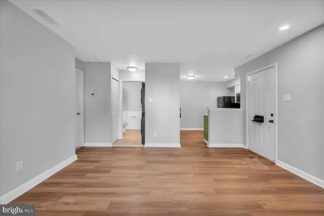 a view of an empty room with wooden floor and a window