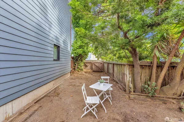 a view of backyard with a table and chairs and wooden fence