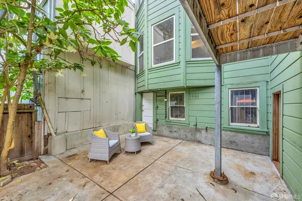 a view of a brick house with chairs and table in a patio