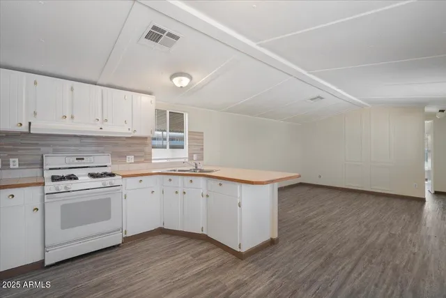 a kitchen with a stove a sink and wooden floor