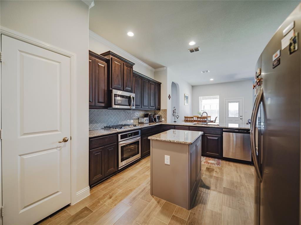 1809 Spinnaker Drive Denton, TX 76210 - Photo 3 of 18 a kitchen with kitchen island granite countertop stainless steel appliances and wooden cabinets