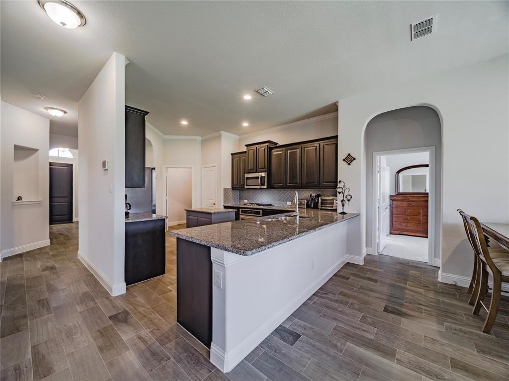1809 Spinnaker Drive Denton, TX 76210 - Photo 6 of 18 a large kitchen with stainless steel appliances kitchen island granite countertop a stove refrigerator and cabinets