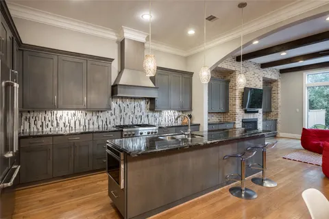 a living room with stainless steel appliances furniture a fireplace and a kitchen view