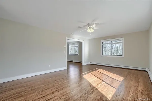 an empty room with wooden floor chandelier fan and windows