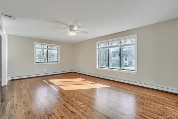 a view of an empty room with a window and wooden floor
