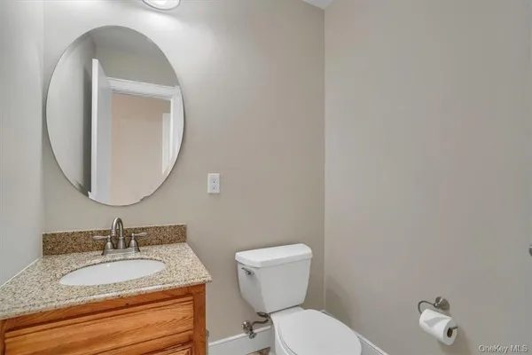 a bathroom with a granite countertop toilet a sink and a mirror