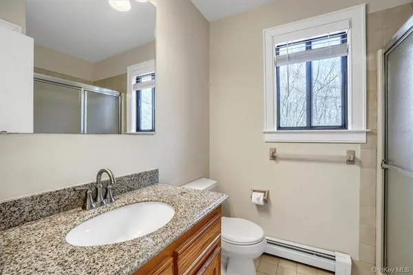 a bathroom with a granite countertop sink a toilet and a mirror
