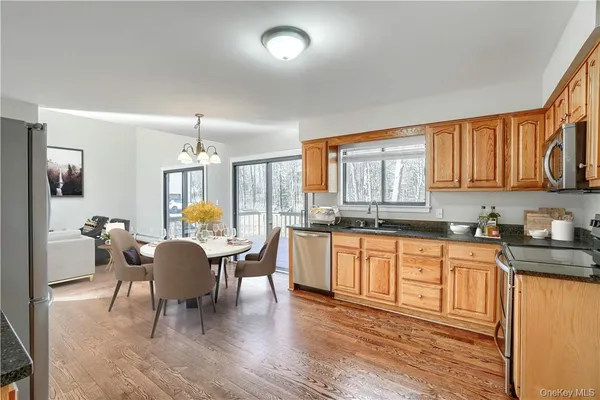 a large white kitchen with granite countertop a stove a sink a dining table and chairs with wooden floor