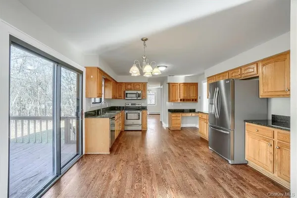 a kitchen with stainless steel appliances granite countertop a refrigerator oven a sink dishwasher and white cabinets with wooden floor