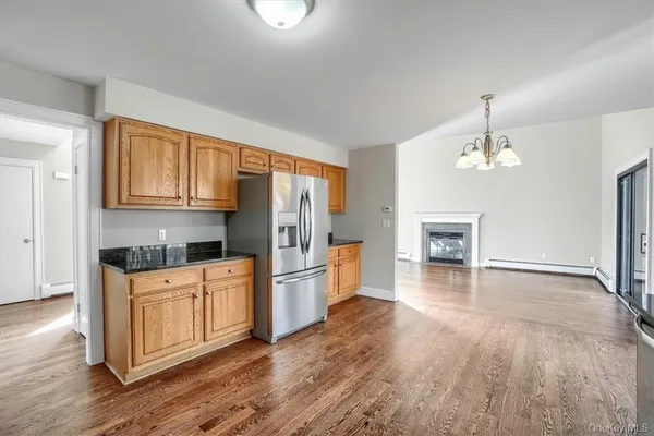 a kitchen with stainless steel appliances granite countertop a refrigerator a stove oven and white cabinets with wooden floor