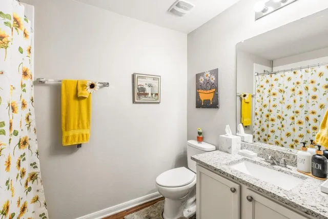 a bathroom with a granite countertop toilet sink and mirror