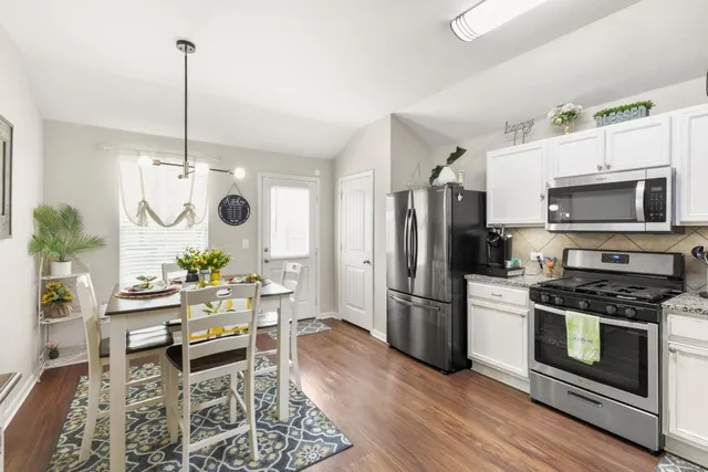 a kitchen with stainless steel appliances a stove a refrigerator and a dining table