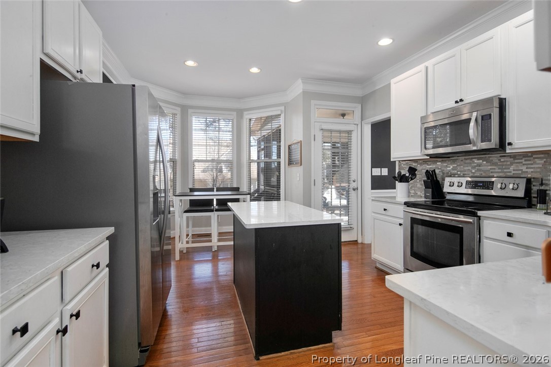 98 Cottswold Lane Spring Lake, NC 28390 - Photo 16 of 30 a kitchen with stainless steel appliances granite countertop a stove top oven a sink dishwasher a refrigerator and a dining table with wooden floor