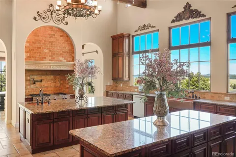 a dining table with a large window and potted plants