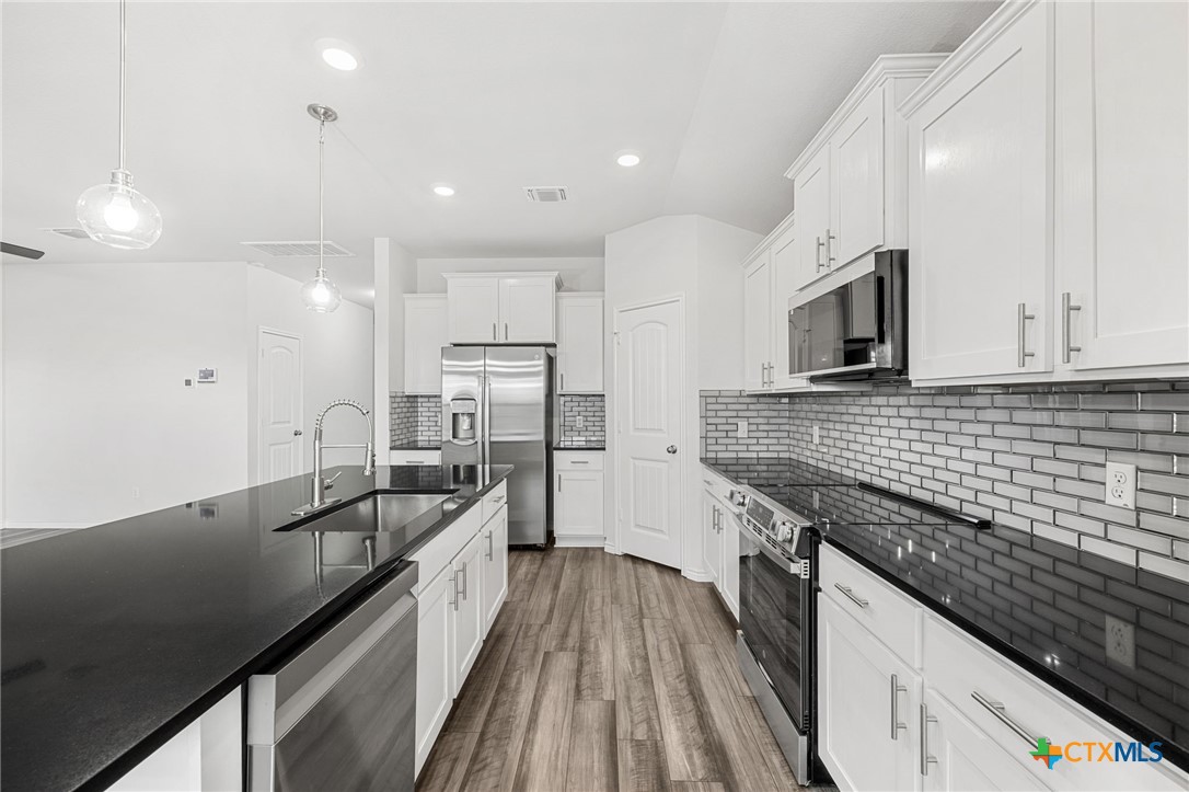 6166 Lavaca Drive Belton, TX 76513 - Photo 14 of 41 a view of a kitchen with a sink and dishwasher a stove top oven with wooden floor