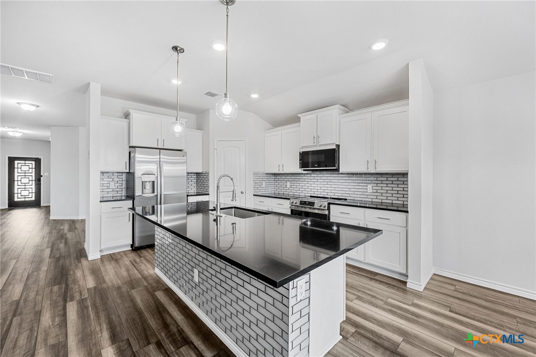 6166 Lavaca Drive Belton, TX 76513 - Photo 15 of 41 a kitchen with stainless steel appliances granite countertop a refrigerator a stove oven a sink dishwasher and white cabinets with wooden floor