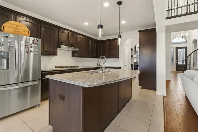 a kitchen with stainless steel appliances granite countertop a refrigerator a sink and a stove