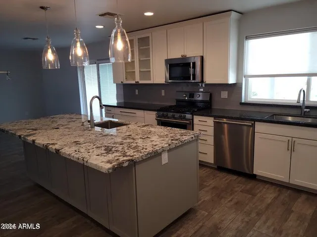 a kitchen with kitchen island granite countertop a sink a counter top space appliances and cabinets