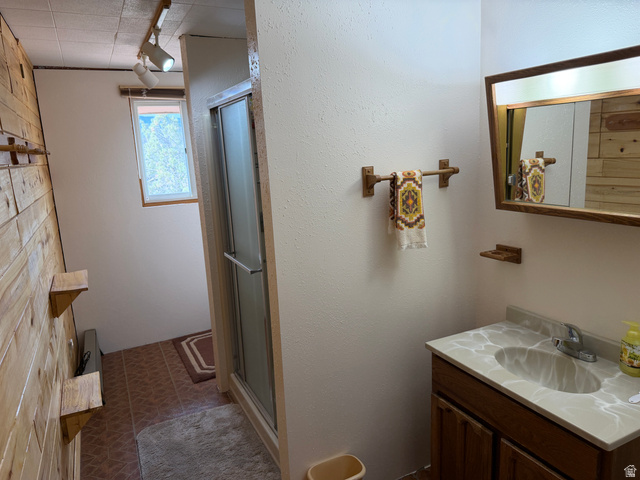 358 South Sky Drive Torrey, UT 84775 - Photo 27 of 82 Bathroom featuring a wood-panel accent wall, tiled flooring, and a glass-enclosed shower