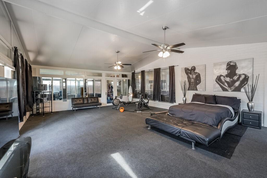 706 Gentry Drive Arlington, TX 76018 - Photo 32 of 39 a spacious bedroom with a bed a couch and a chandelier