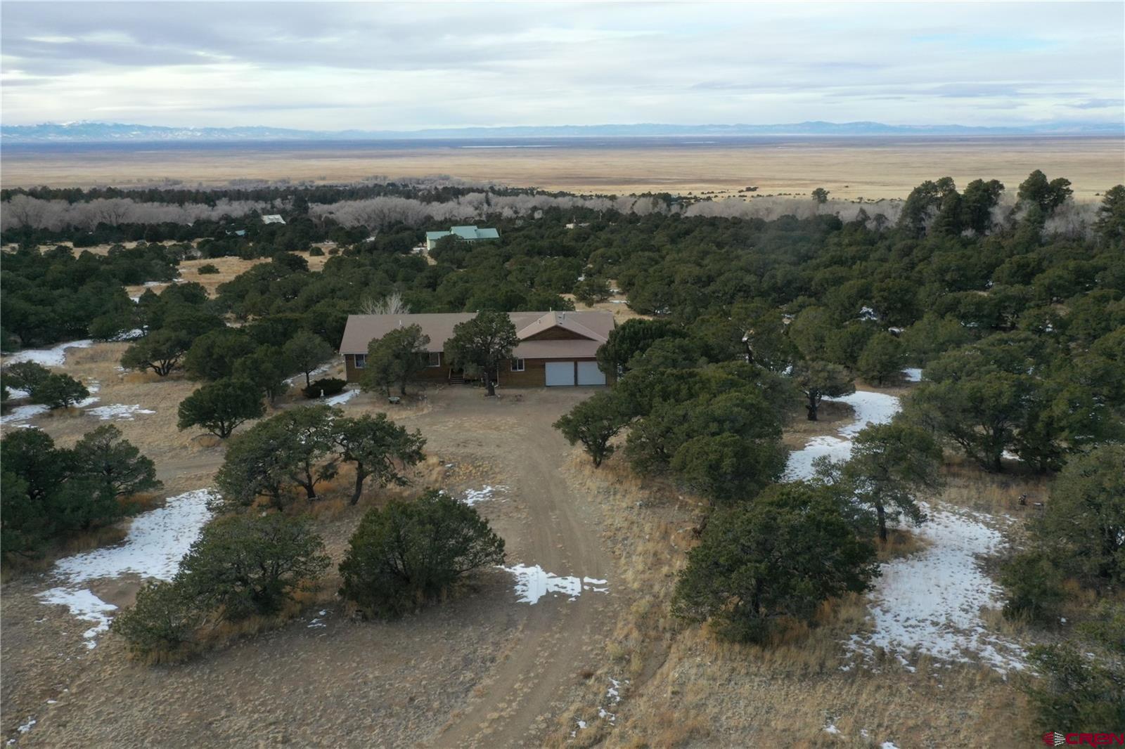 105 Indian Hill Road Mosca, CO 81146 - Photo 2 of 38 There is a circular driveway with Pinion Trees and Juniper trees. Over the horizon is the valley floor which sits at an elevation of 75,049ft. West view - you can see the San Juan Mountain range.