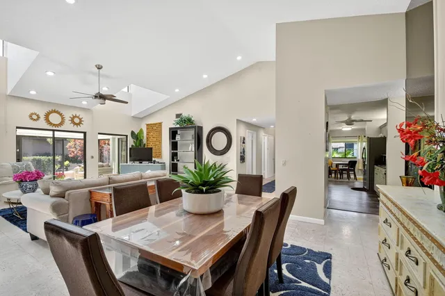 a kitchen with stainless steel appliances kitchen island granite countertop a stove top oven a sink a dining table and chairs with white cabinets