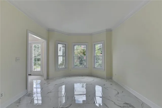 a view of an empty room with window and chandelier
