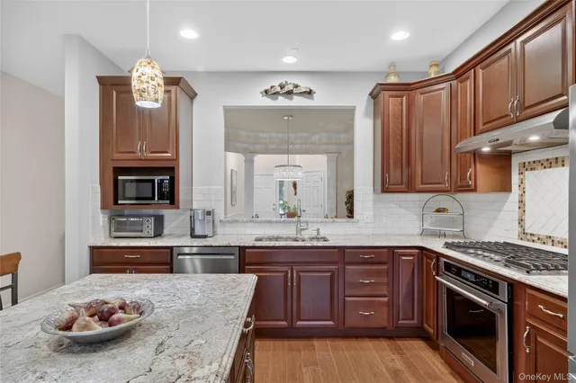 a kitchen with stainless steel appliances granite countertop a stove top oven a sink dishwasher a dining table and chairs with wooden floor