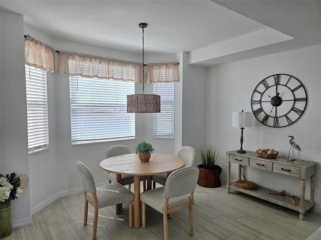 19116 Scallop Loop, Unit 303 Lakewood Ranch, FL 34211 - Photo 11 of 32 a dining room with wooden floor a chandelier a wooden table and chairs