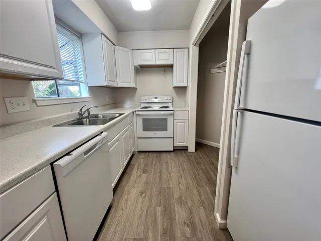 a kitchen with a sink a refrigerator a window and cabinets