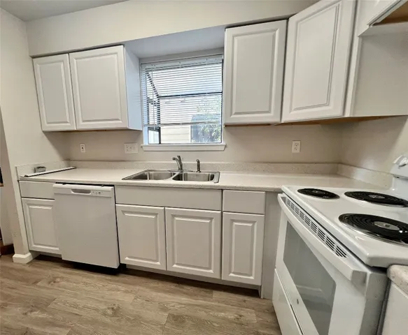 a kitchen with granite countertop white cabinets and white appliances