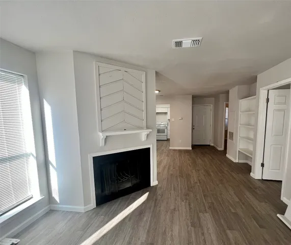 an empty room with wooden floor and fireplace