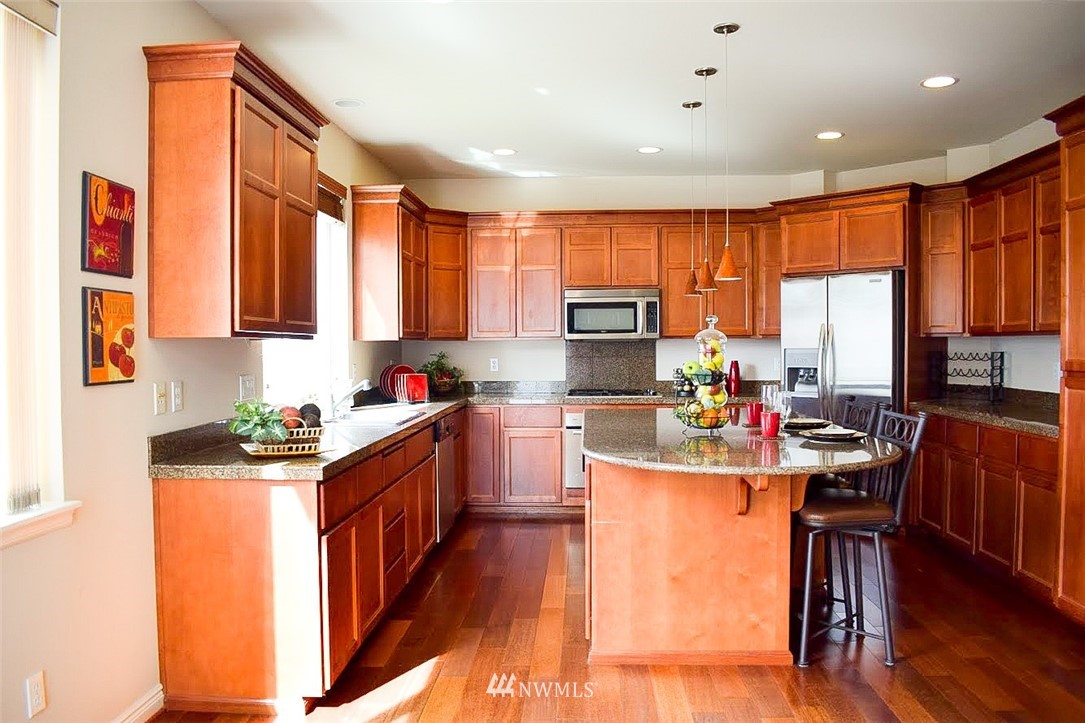 1217 South 36th Place Renton, WA 98055 - Photo 7 of 15 a kitchen with stainless steel appliances granite countertop sink stove top oven and cabinets