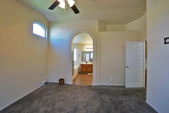 a view of an empty room with chandelier fan and fire place