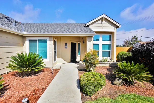 a view of a house with a yard and potted plants