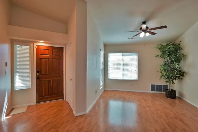 a view of hallway with an empty room and wooden floor