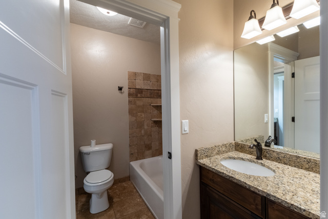 3565 West 1350th Street North Vernal, UT 84078 - Photo 47 of 54 Bathroom featuring a granite-look countertop, wood-finish vanity, and a tiled tub surround