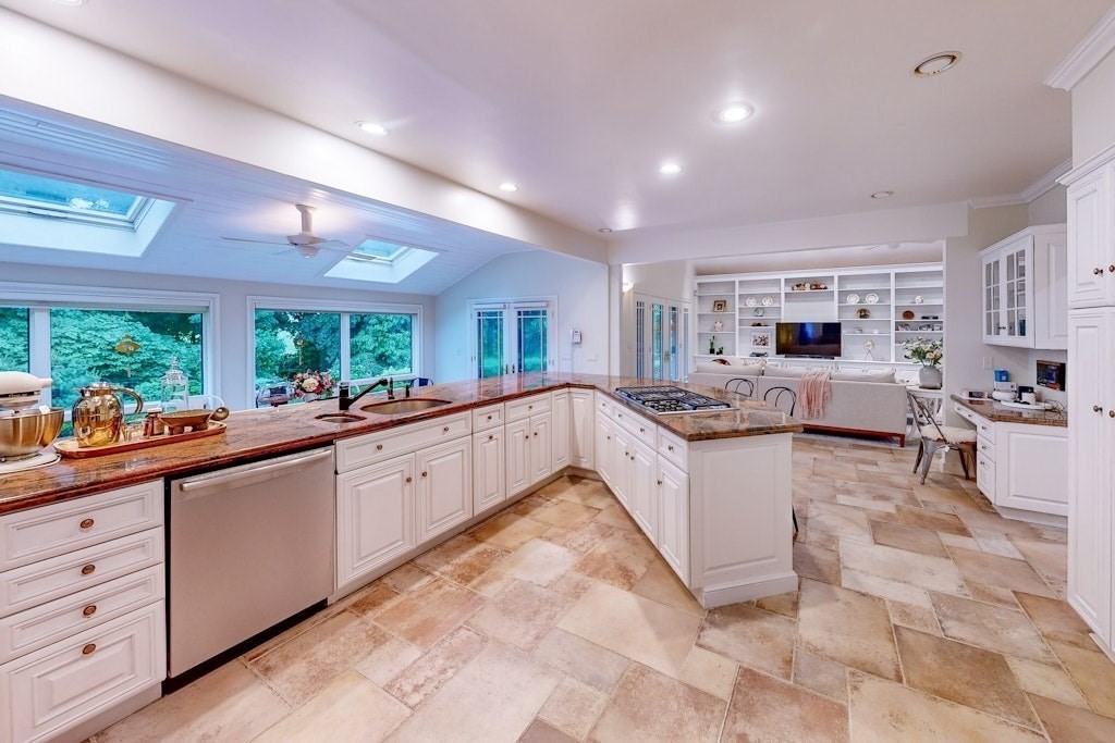 a large white kitchen with lots of counter space cabinets and a potted plant